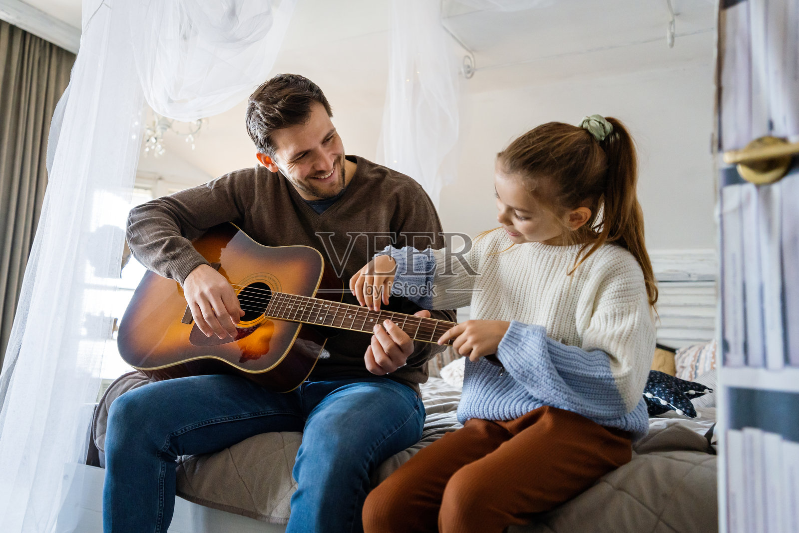 快乐的单身父亲在家教女儿弹吉他。照片摄影图片