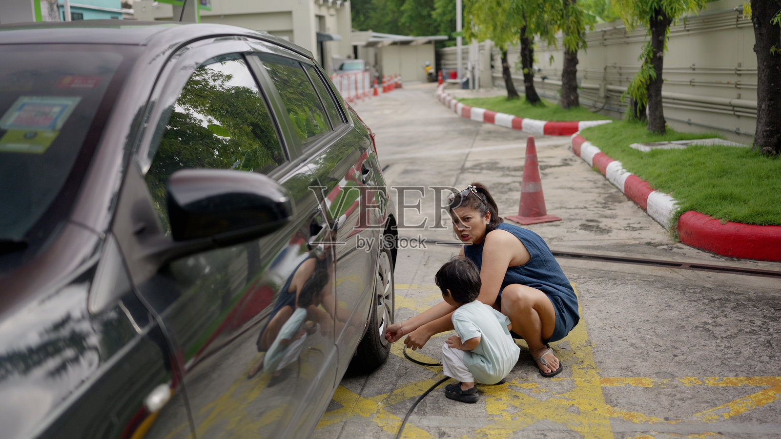 亚洲母亲和孩子正在给汽车充气。照片摄影图片