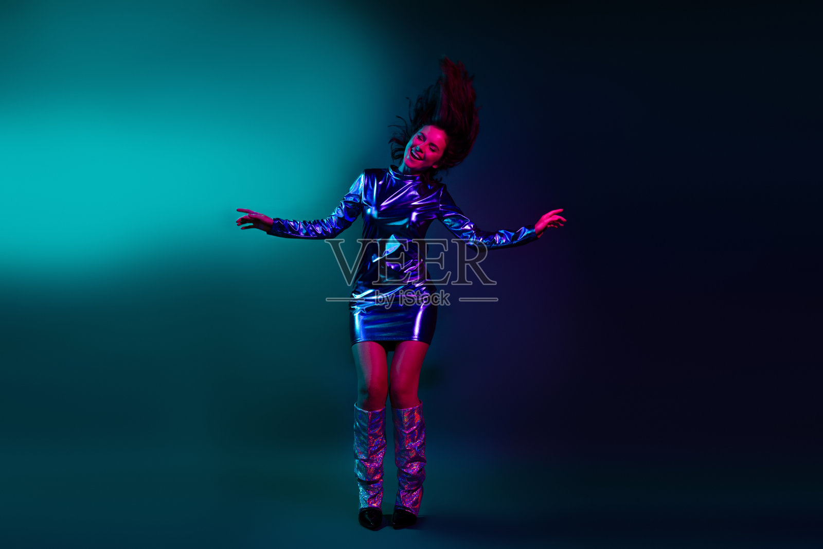 全身肖像，迷人的年轻女孩穿着闪亮的舞蹈服，在深蓝色背景下享受霓虹灯的氛围。照片摄影图片