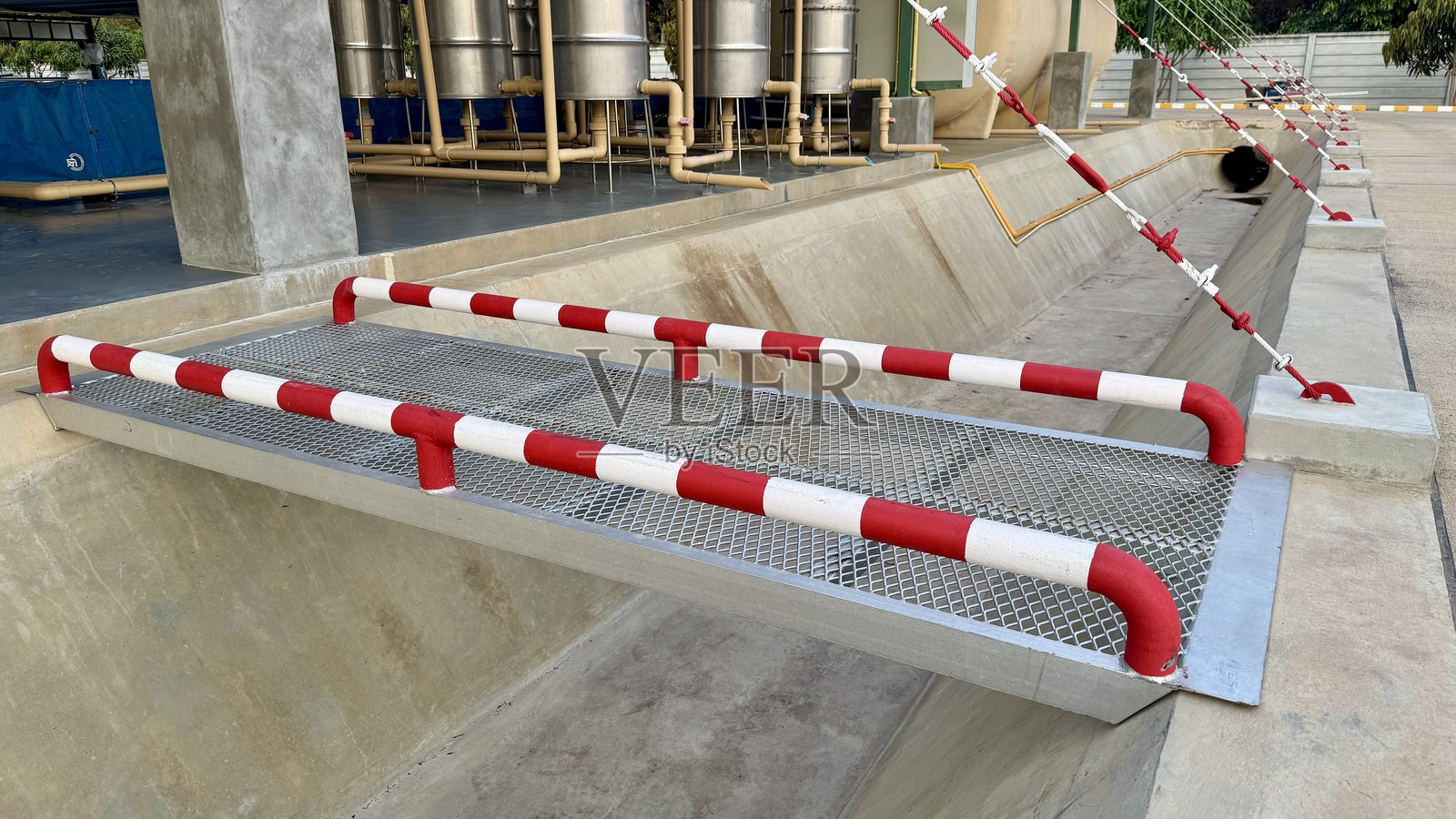 带安全护栏的工业装卸坡道 近距离拍摄一座坚固的工业装卸坡道，配有红白相间的安全护栏，为重型车辆和设备提供安全高效的通道。照片摄影图片