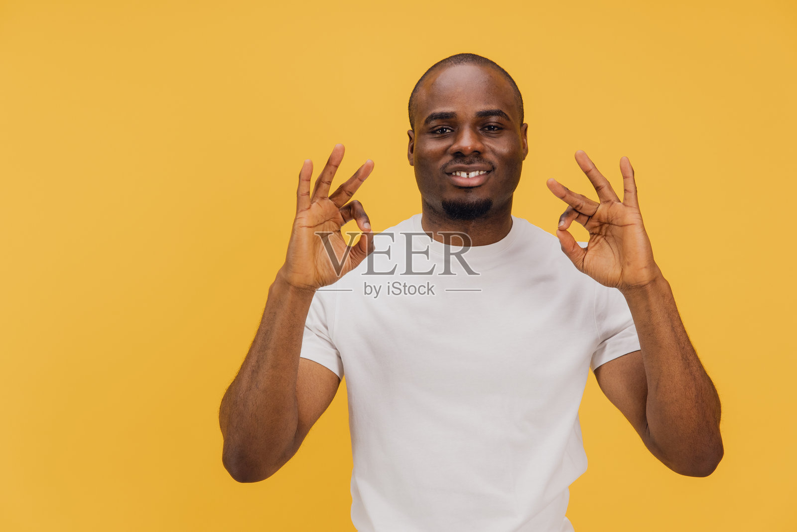 年轻男子在黄色背景下用双手做出“好”手势照片摄影图片