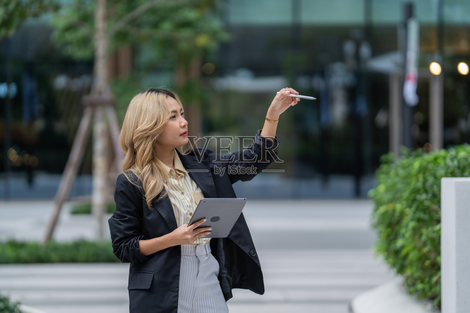 专注的女商人在城市环境中使用平板电脑和触控笔。展示现代科技、精准和专业，适合创新和生产力主题。照片摄影图片