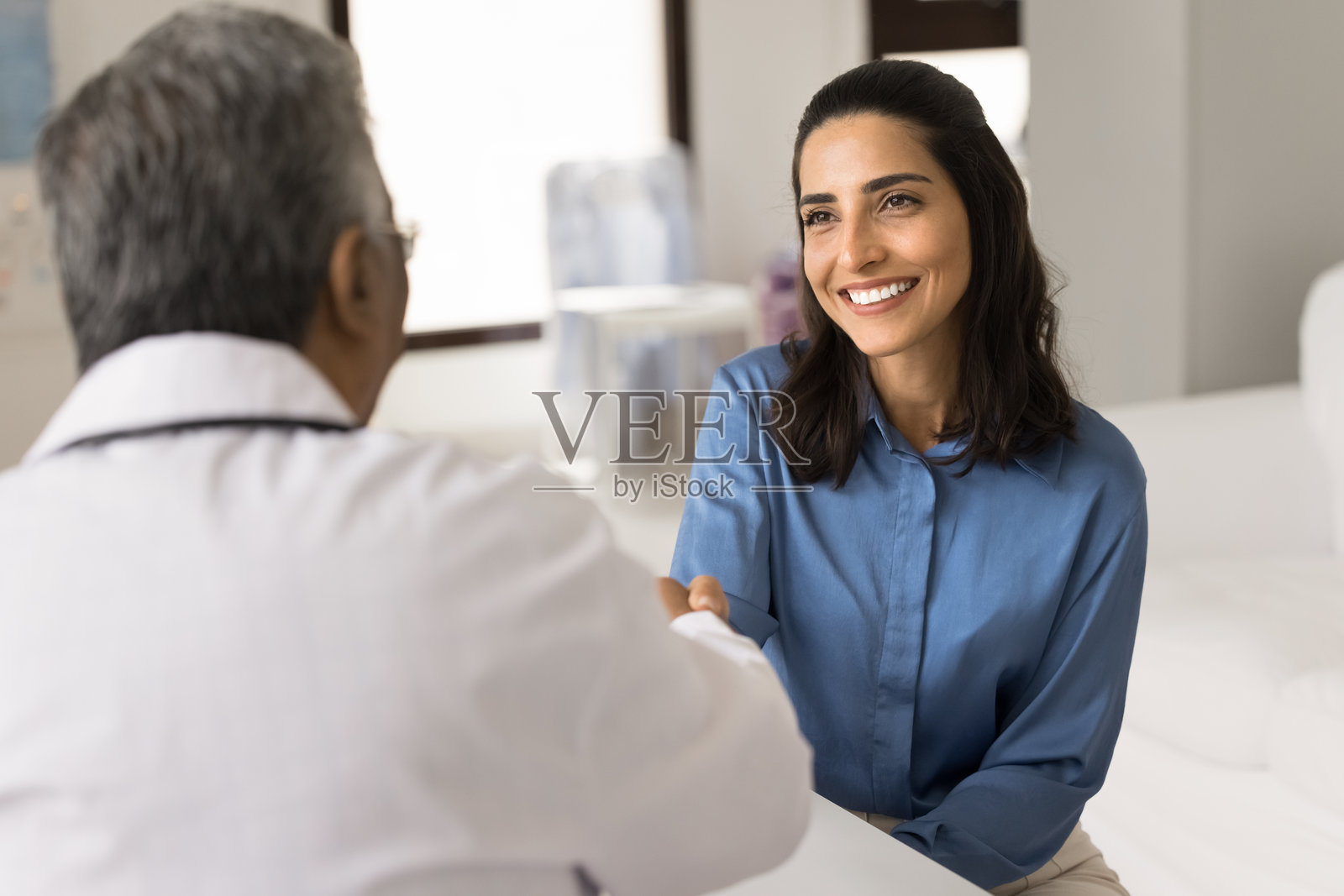 年长的治疗师向年轻迷人的拉丁裔女性患者问好照片摄影图片