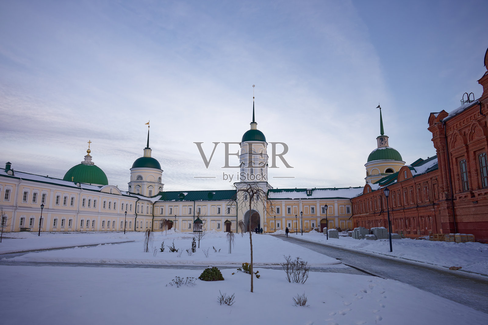 一座带有绿色圆顶的大楼坐落在雪-covered的庭院中照片摄影图片