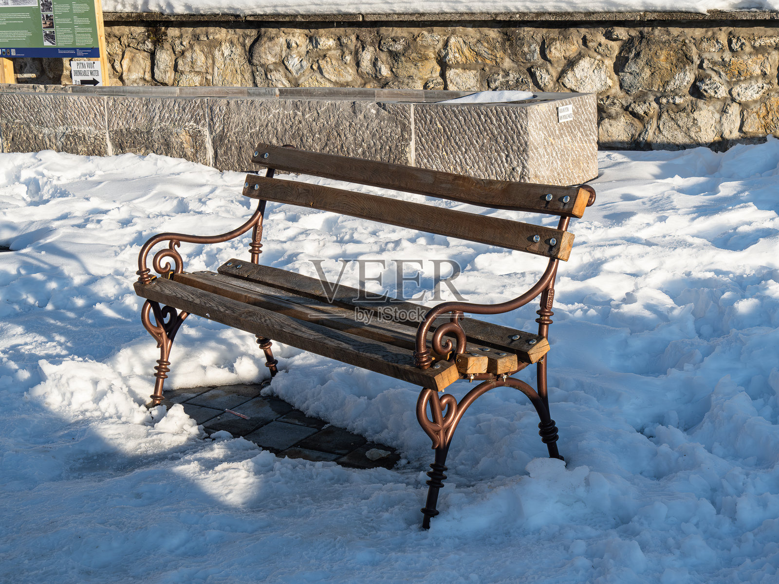 一张复古的木长椅，配有华丽的金属腿，部分被雪覆盖。照片摄影图片