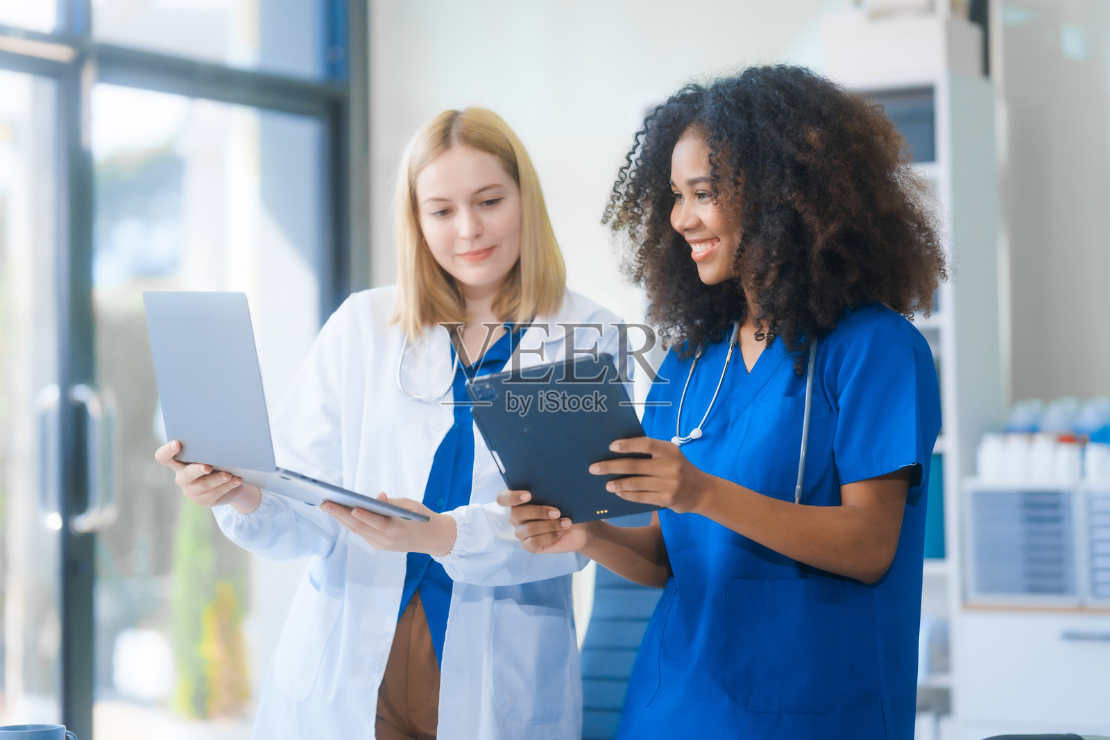 年轻的非裔美国女性和俄罗斯女性，都是科学家，合作使用显微镜分析血样、病毒和疫苗。他们进行重要的医学和生物研究。照片摄影图片