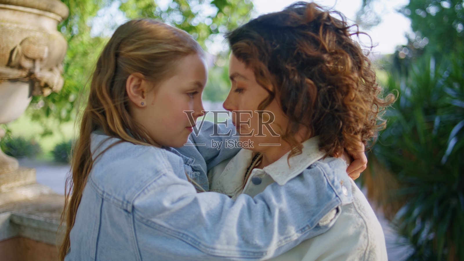 母女在城市花园中亲密接触，女人抱着孩子的特写镜头。照片摄影图片
