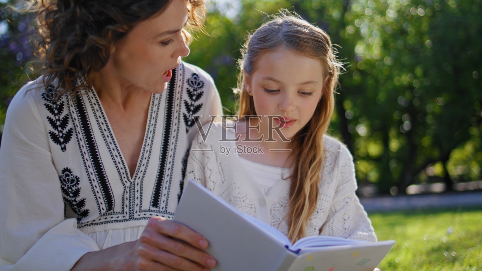 快乐的家庭在舒适的花园中聚会阅读书籍，特写镜头。女人和女孩在休息。照片摄影图片
