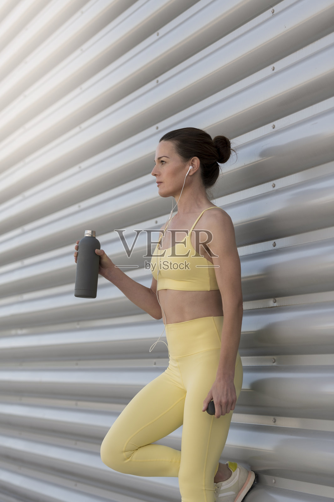 运动女性在户外锻炼后休息并拿着一瓶水照片摄影图片