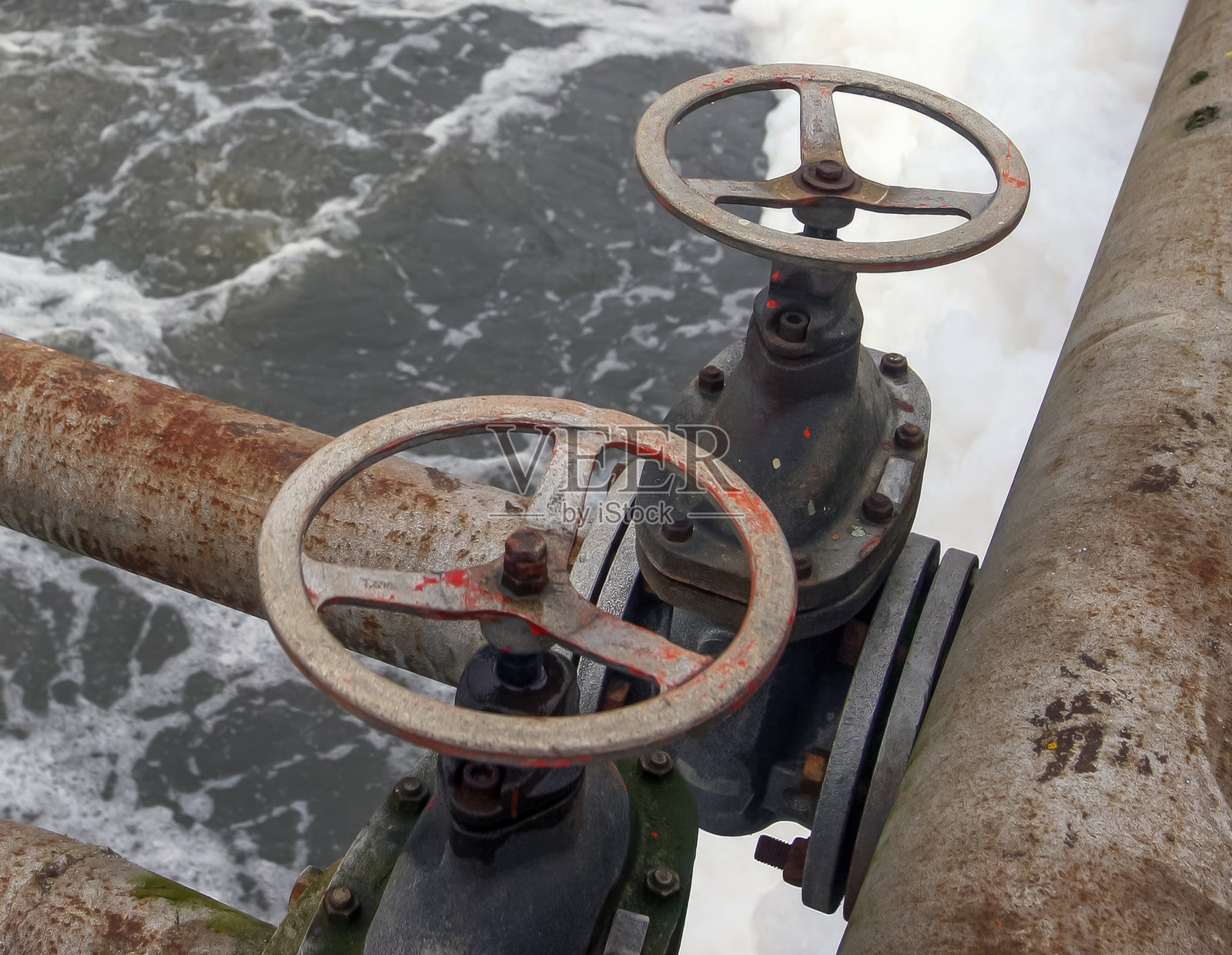 老旧的水处理厂阀门俯瞰着在白天流淌的河流照片摄影图片