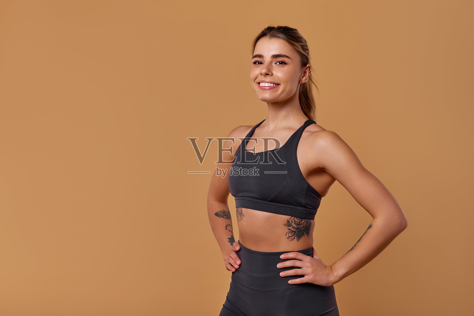 一位自信的年轻女性健身模特穿着时尚的运动服，背景简单。照片摄影图片