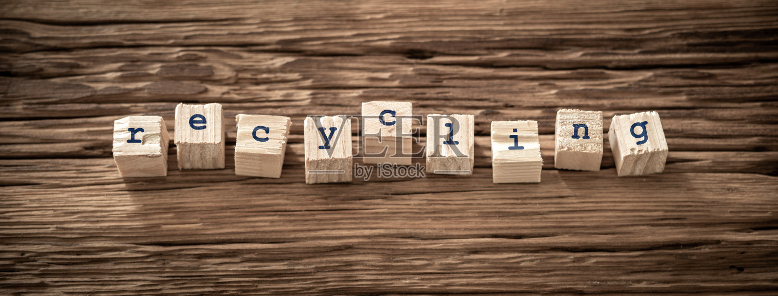在粗糙的木质表面上拼写“回收”的木块，突显可持续实践和环保理念照片摄影图片
