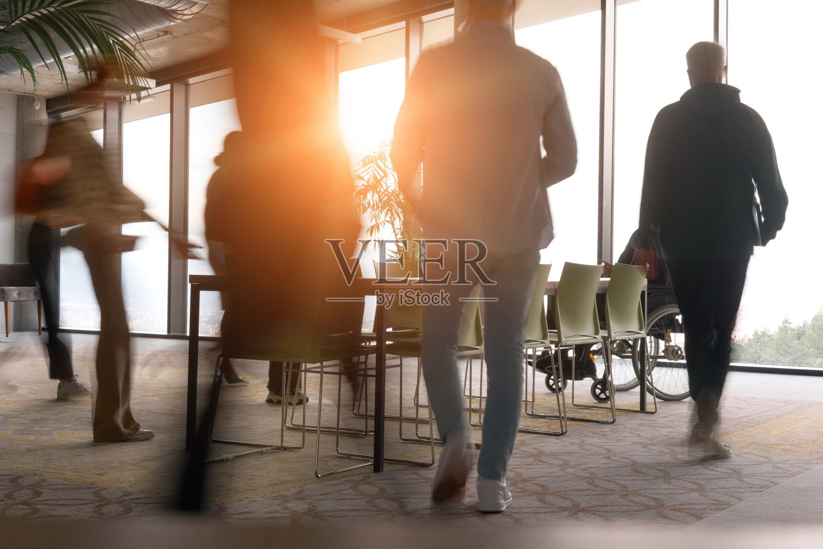 一个多元化的商业团队在会议桌旁紧急工作，协作开会，他们的主管坐在轮椅上等待他们的意见。照片摄影图片