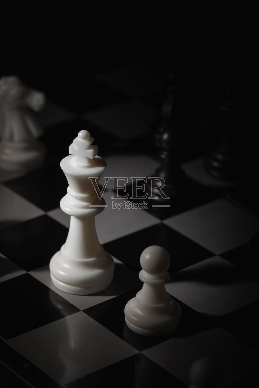 特写镜头展示了一个棋盘，白色国王在黑色棋子中格外显眼。照片摄影图片