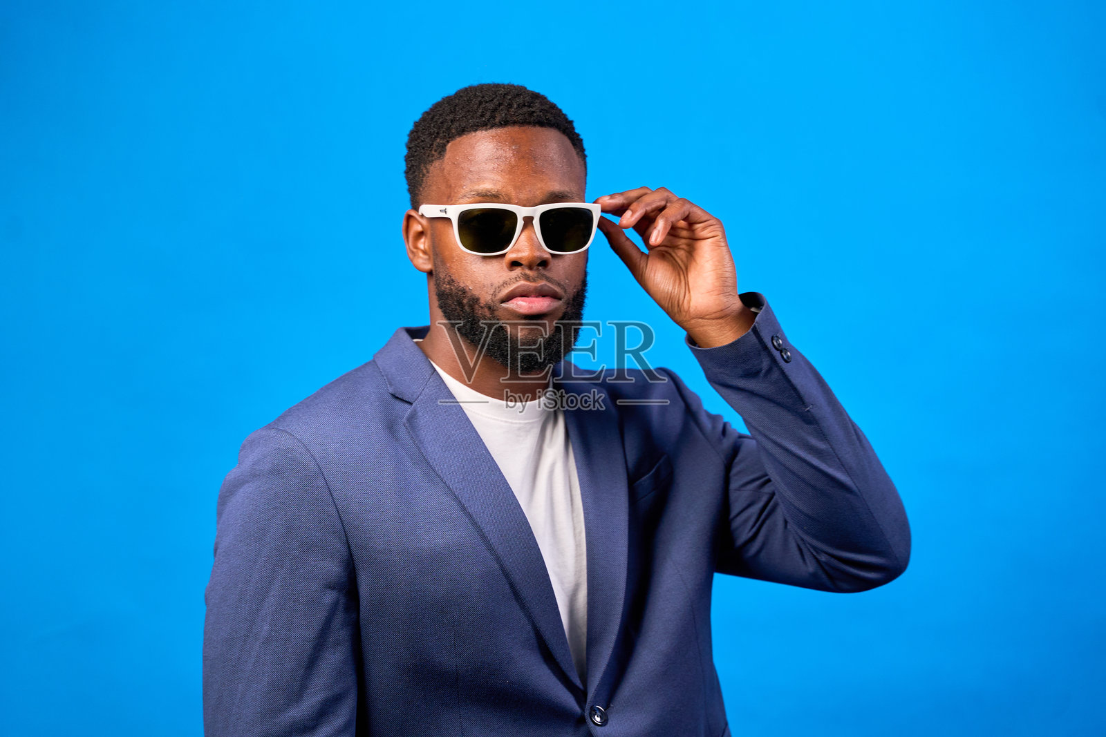 时尚的企业家在蓝色背景下调整太阳镜照片摄影图片