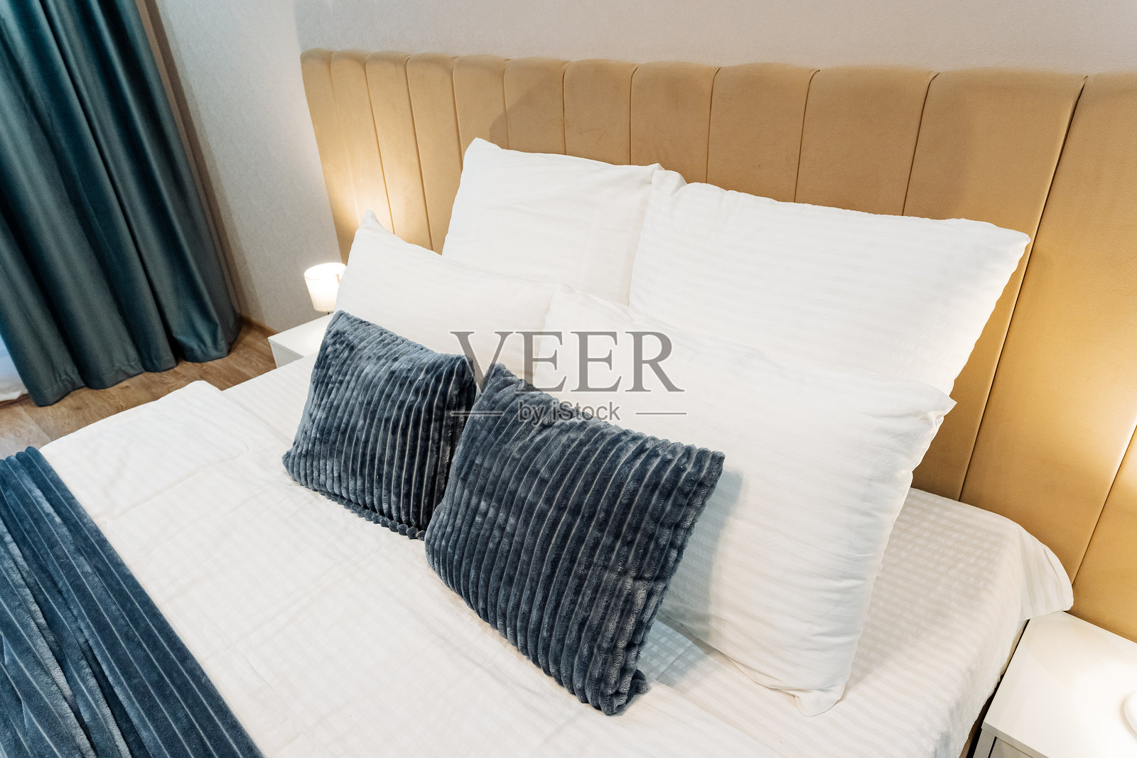 在一个设计精美的酒店房间里，有一张整洁的床，铺着洁白的床单和鲜艳的蓝色枕头，为客人营造了一个舒适宜人的氛围。照片摄影图片