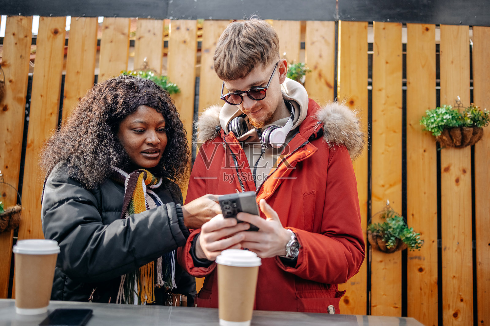 大学生在户外人行道咖啡馆休息，查看手机。照片摄影图片