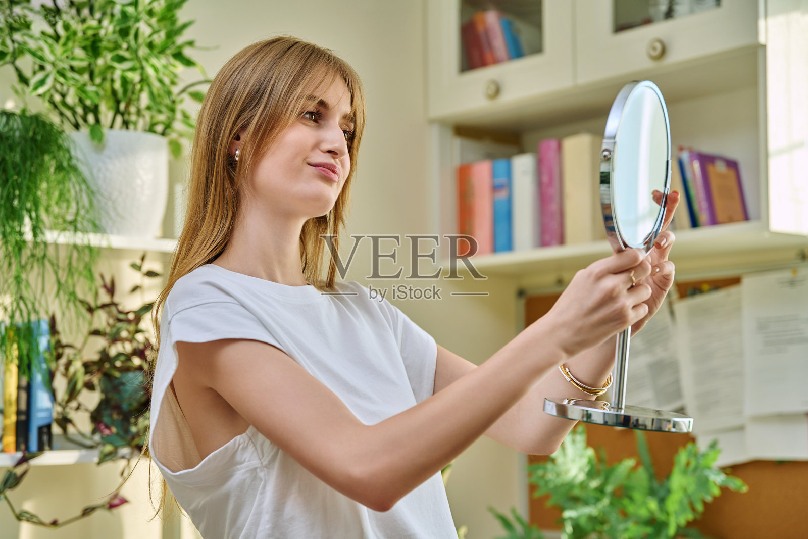 年轻漂亮的女人在镜子前查看面部、头发、皮肤和妆容照片摄影图片