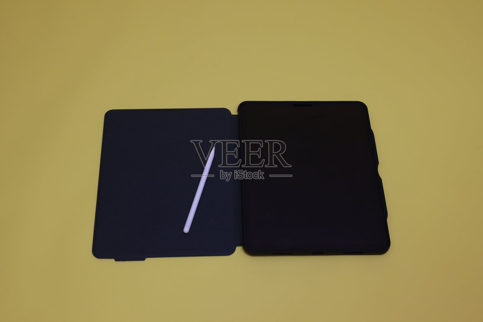 一台空白屏幕的数字平板电脑和一支数字笔，背景为黄色。照片摄影图片