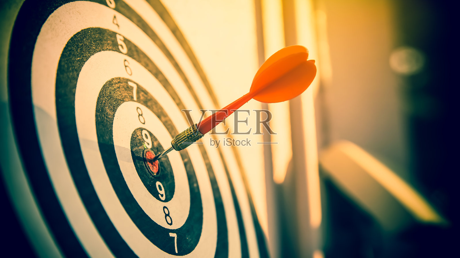 靶心或飞镖板上红色飞镖箭头击中射击目标中心，象征着商业目标的精准定位与成功达成。照片摄影图片