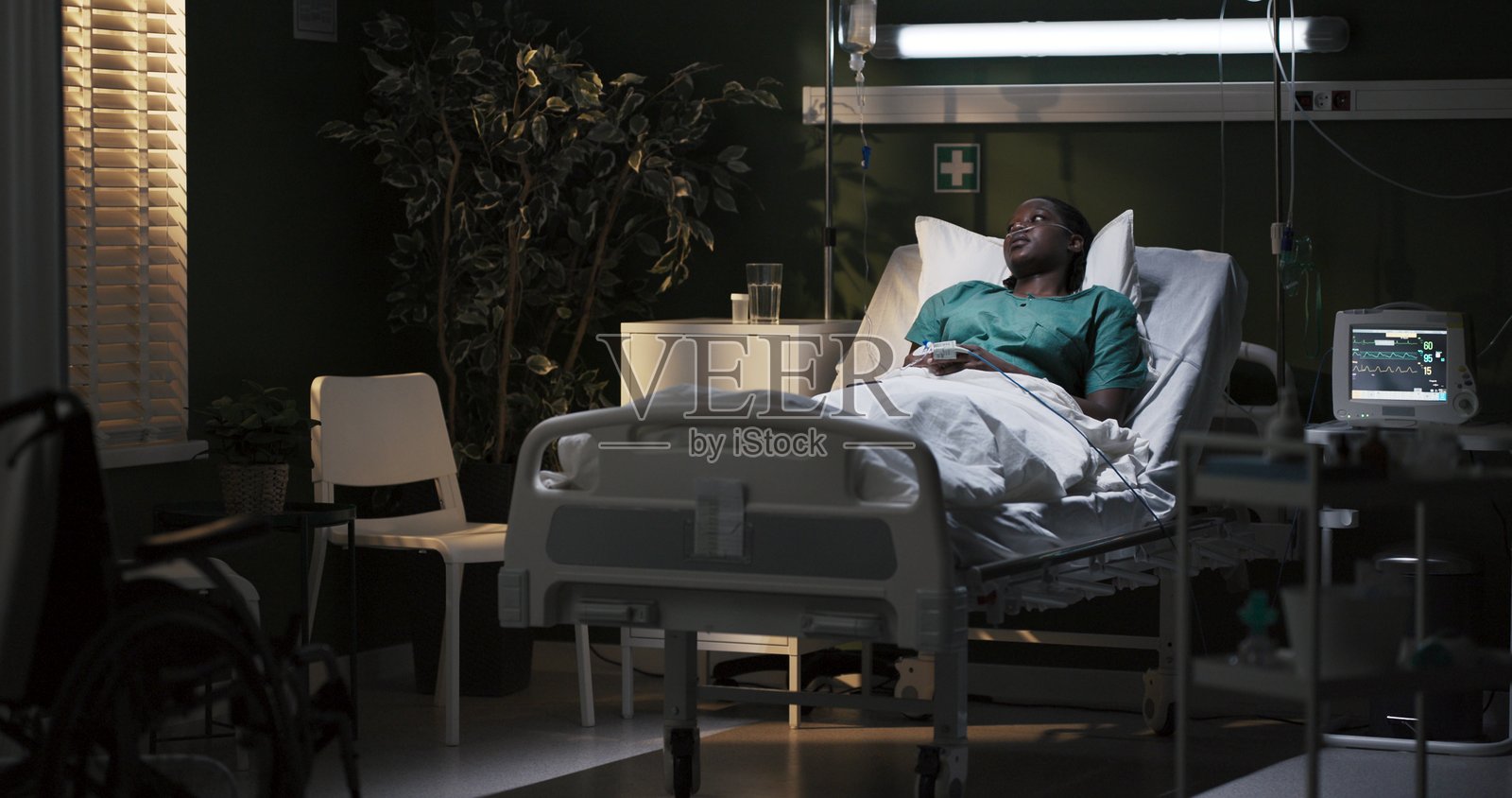 悲伤的非洲女性躺在床上，拿起电话与家人交谈，同时在医院中感到欣喜。照片摄影图片