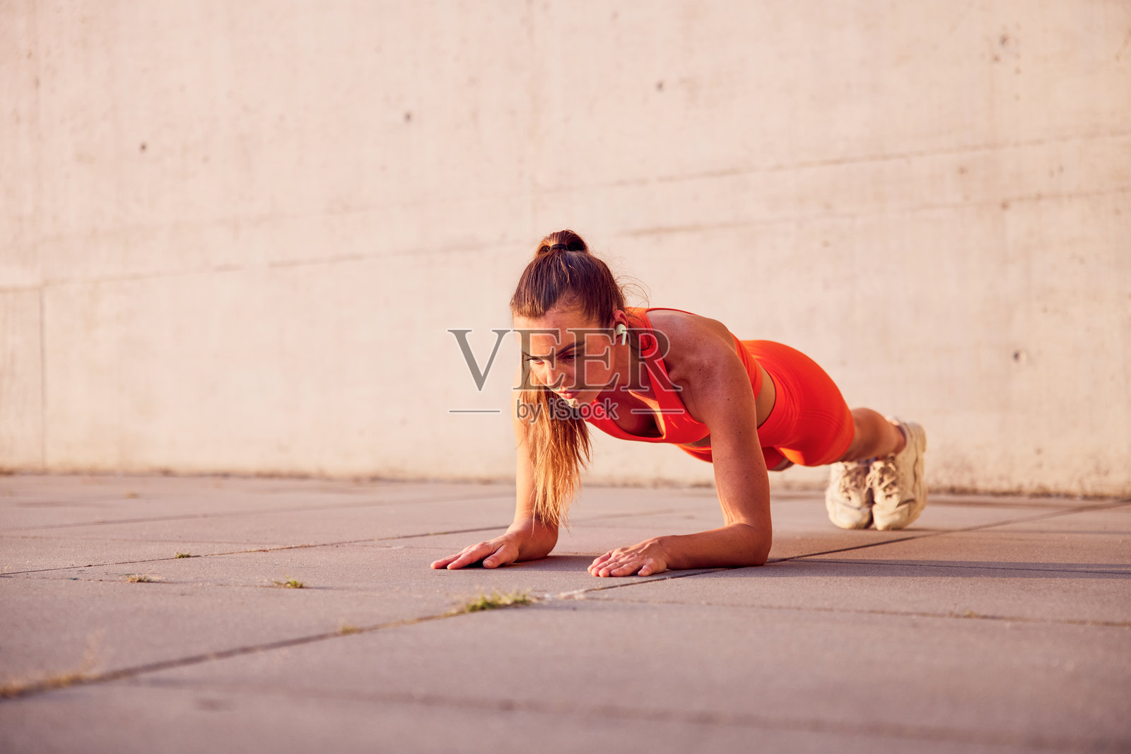 穿着橙色运动服的健康女性在户外做平板支撑锻炼照片摄影图片