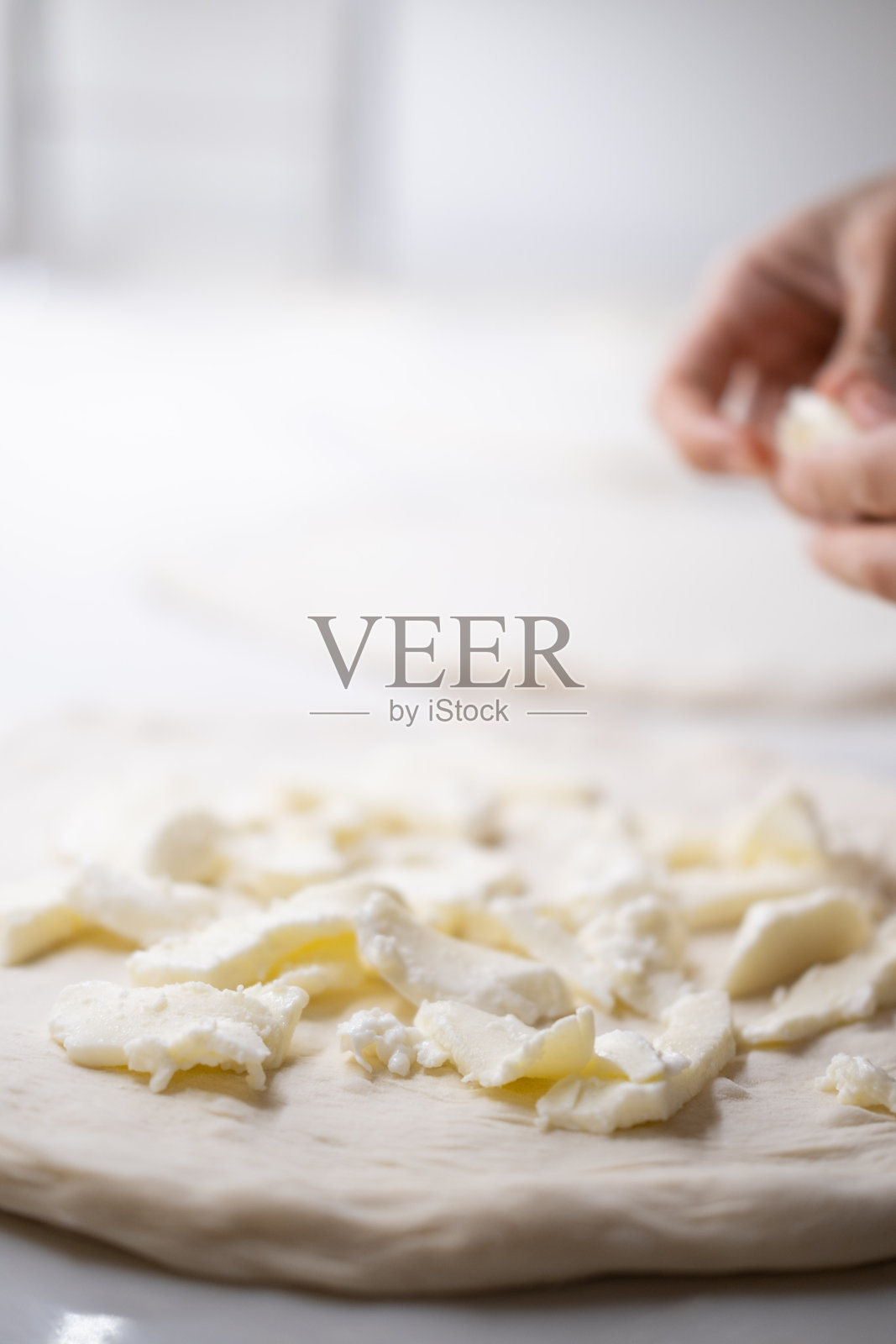 新鲜马苏里拉奶酪块的生披萨面团特写，展示了专业披萨厨房中的传统意大利披萨制作过程，突显新鲜食材和手工艺。照片摄影图片