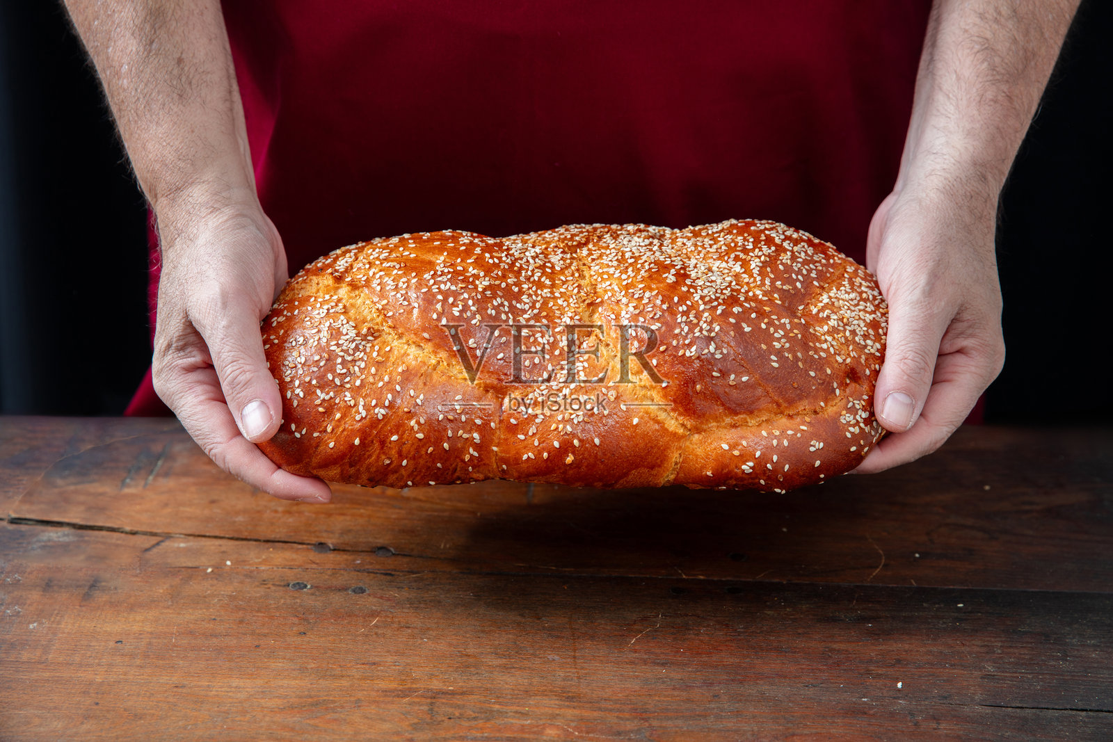 复活节甜面包，面包师的手在木桌上托着一条茨乌雷基编织面包，特写镜头照片摄影图片