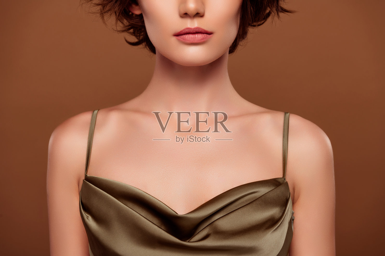 时尚卡其色服装的漂亮年轻女孩胸部特写照片，背景为棕色。照片摄影图片