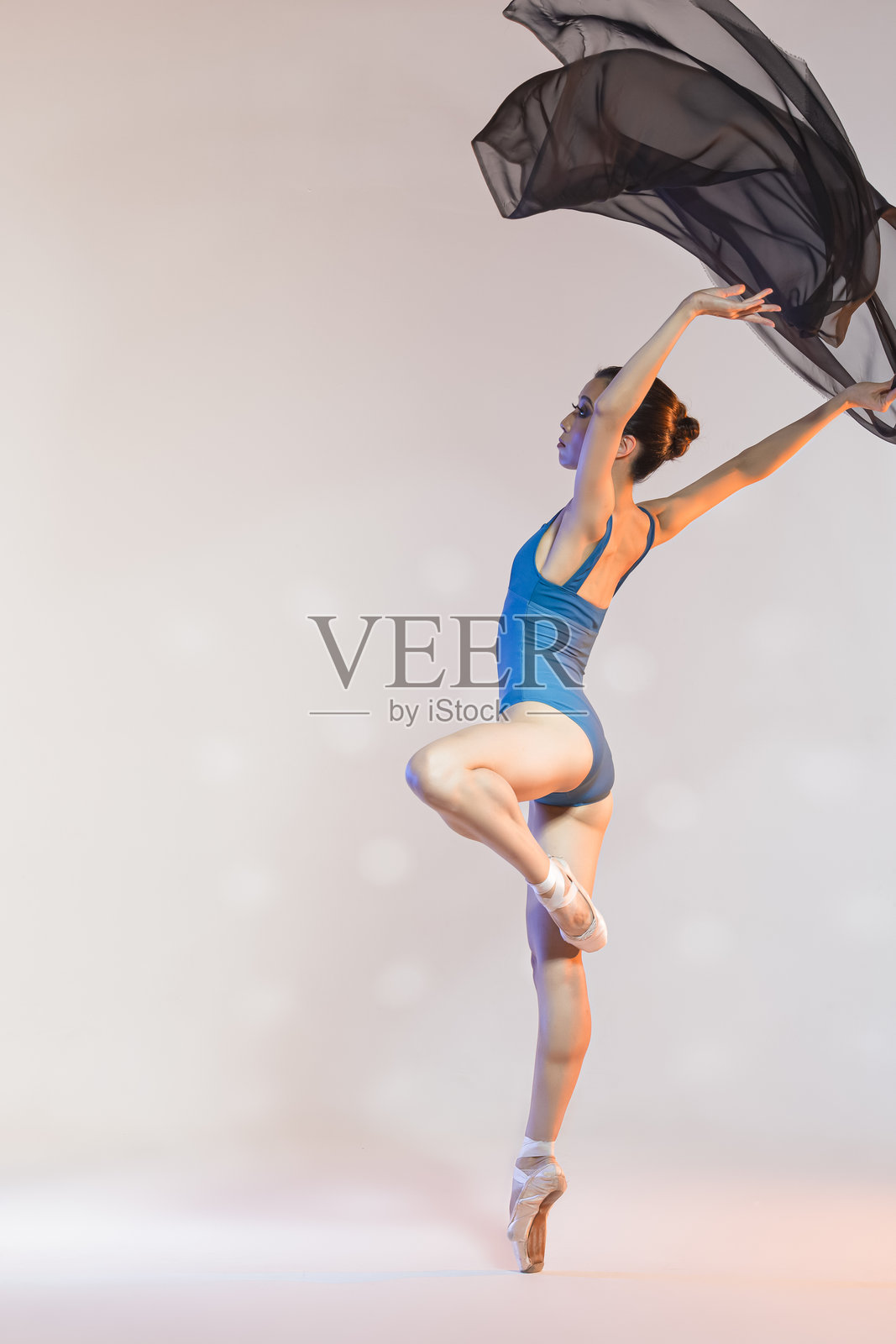 女性芭蕾舞者身穿蓝色泳衣裙，手中挥舞着黑色布料，展现芭蕾概念的创意。照片摄影图片