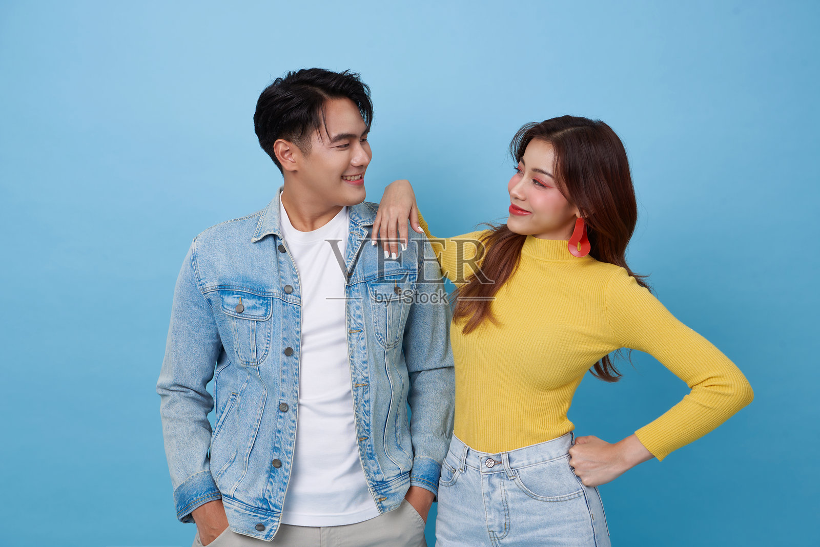 快乐的年轻亚洲情侣相拥在一起，面朝面地凝视，背景为蓝色。照片摄影图片