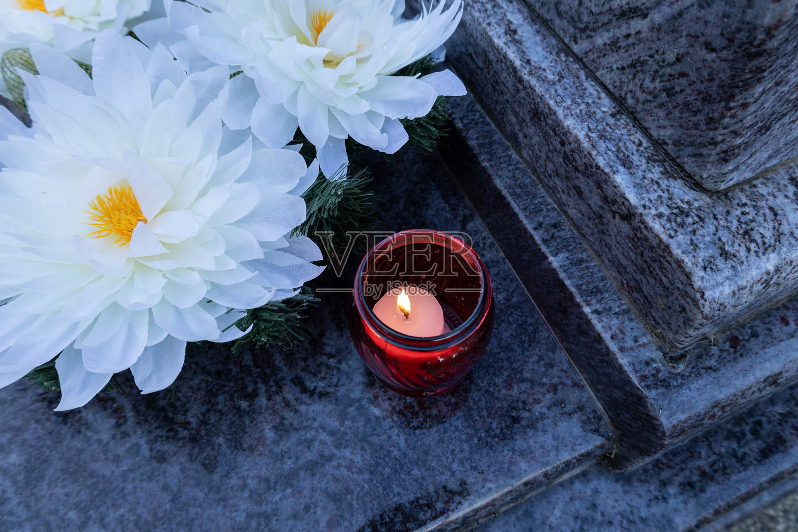 墓碑上摆放着白色花朵和红色蜡烛灯笼照片摄影图片