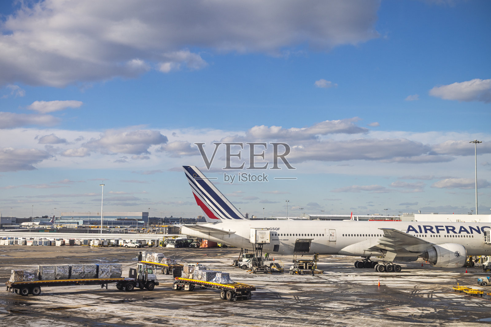 法国航空的波音777停在停机坪上，周围有装载集装箱的卡车。照片摄影图片