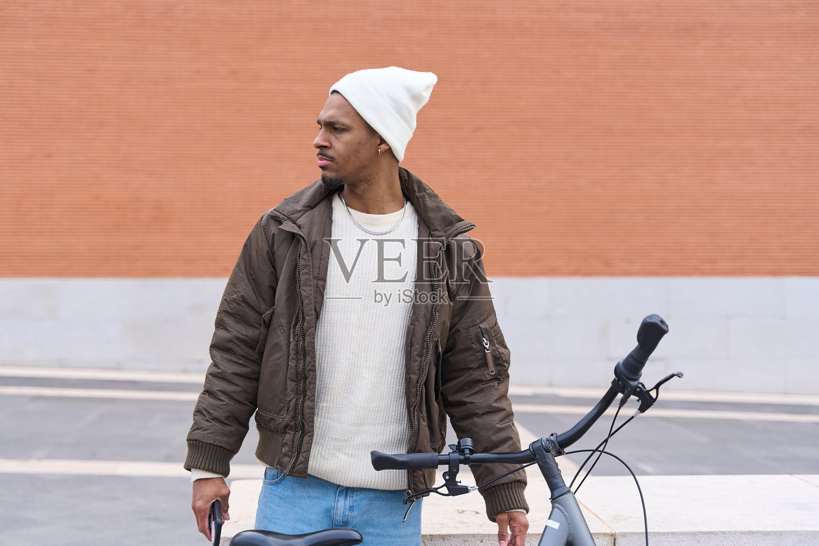 时尚男士在城市中摆姿势，手持自行车并向一旁望去照片摄影图片