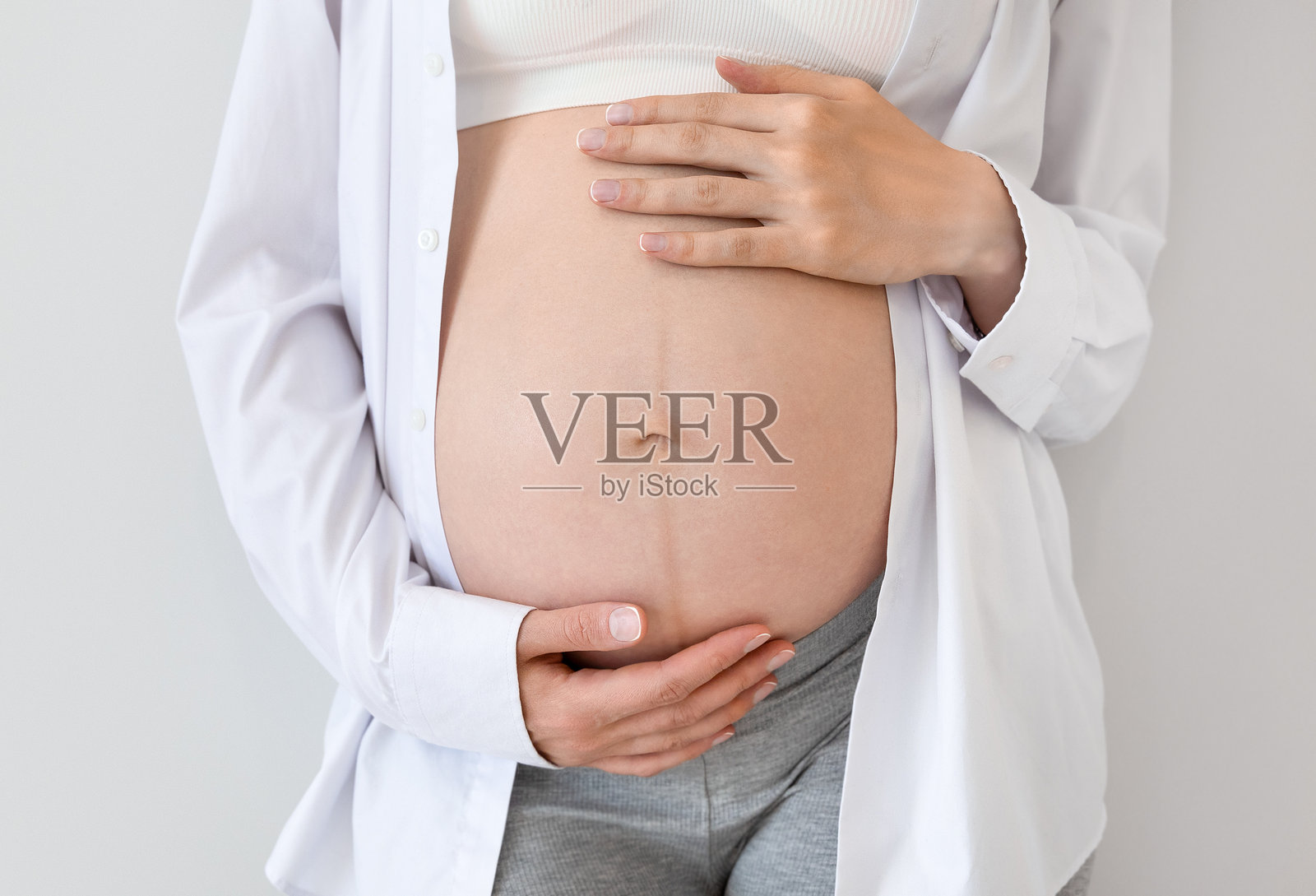 孕妇轻抚她的肚子照片摄影图片