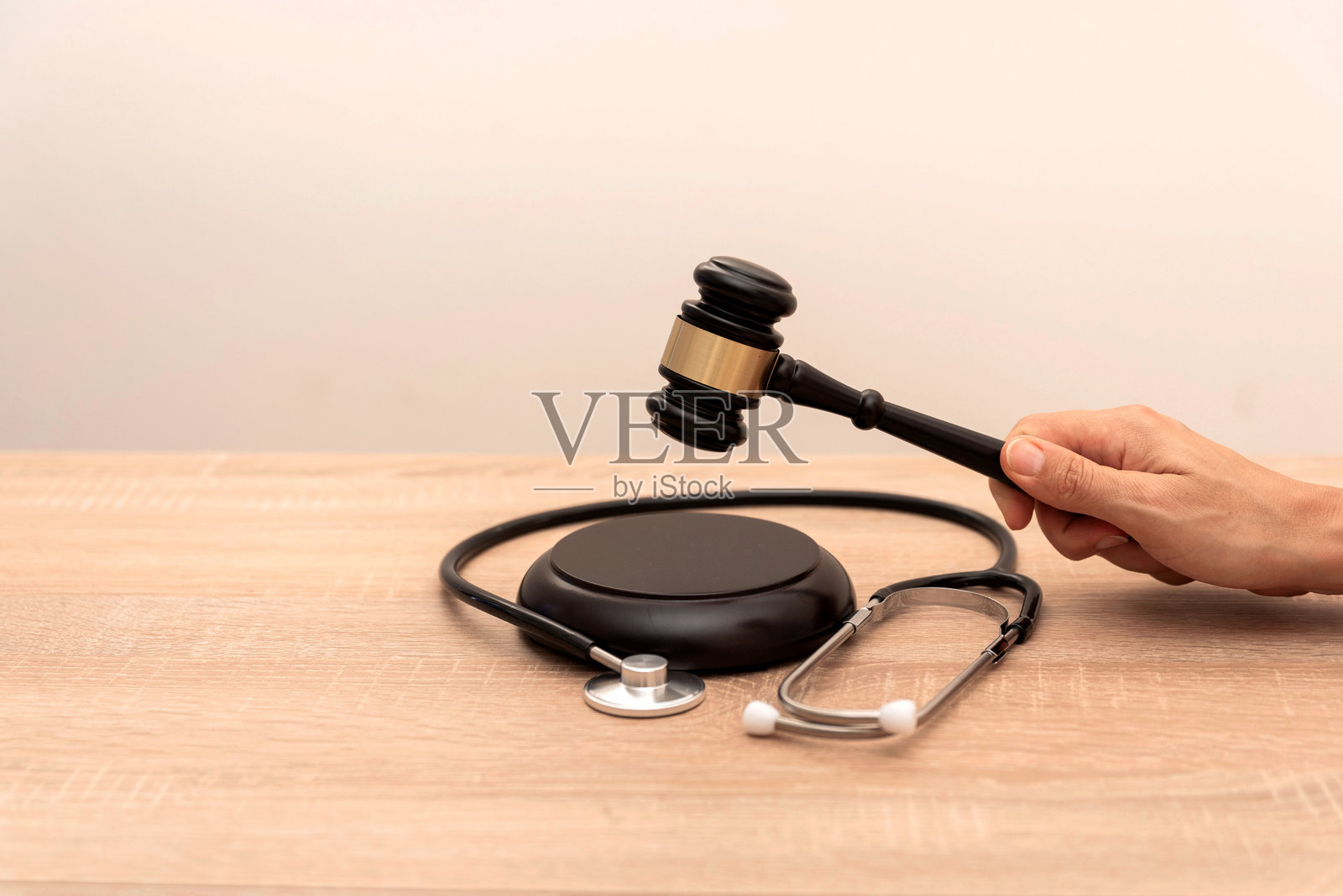 手握法槌与听诊器的特写，放在木桌上，医疗法律与正义概念照片摄影图片
