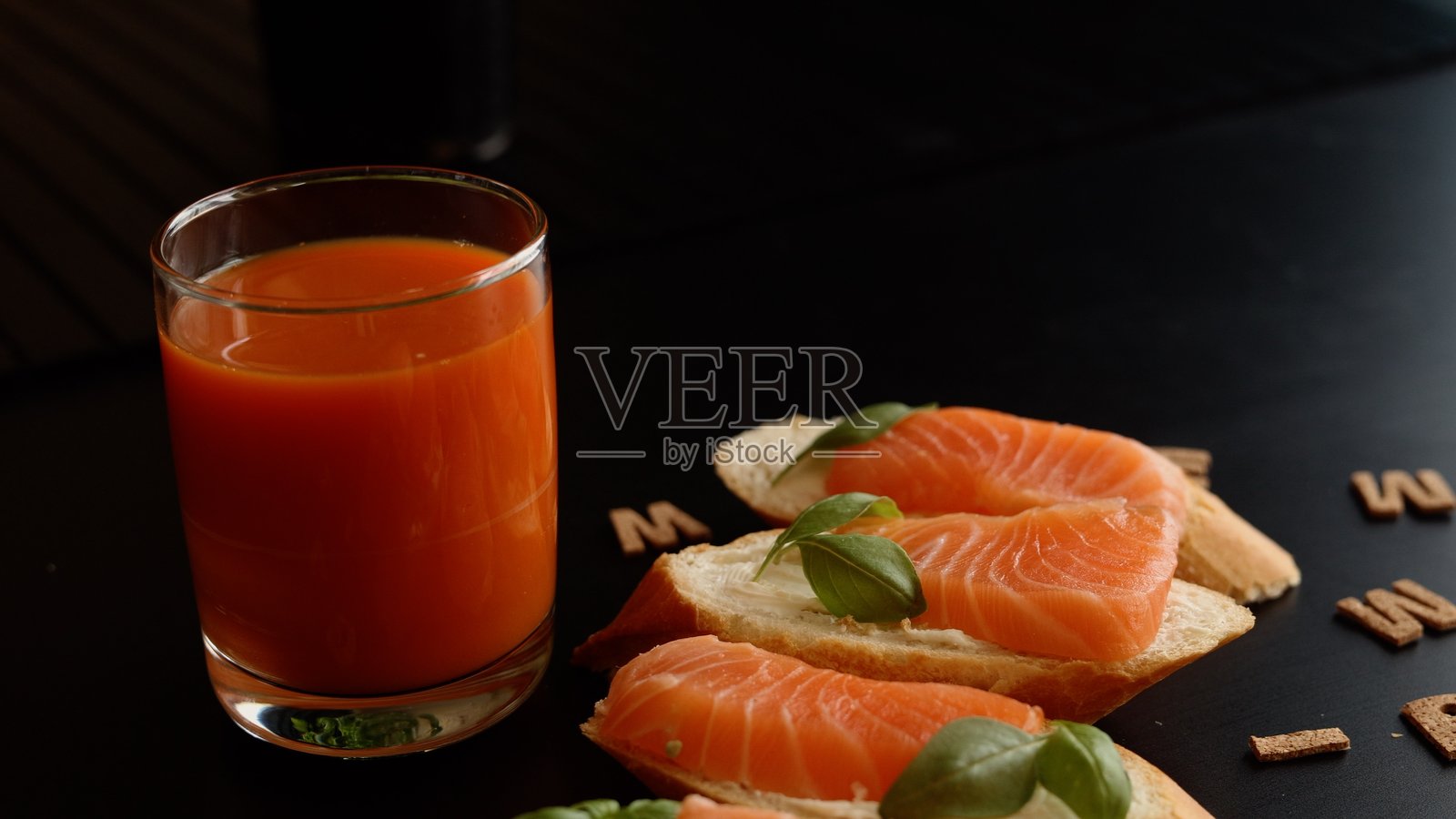 新鲜罗勒和奶酪的三文鱼为经典三明治带来了现代风味。搭配橙子胡萝卜汁，这道环保餐点结合了丰富的口味和健康益处，满足了饮食需求。照片摄影图片