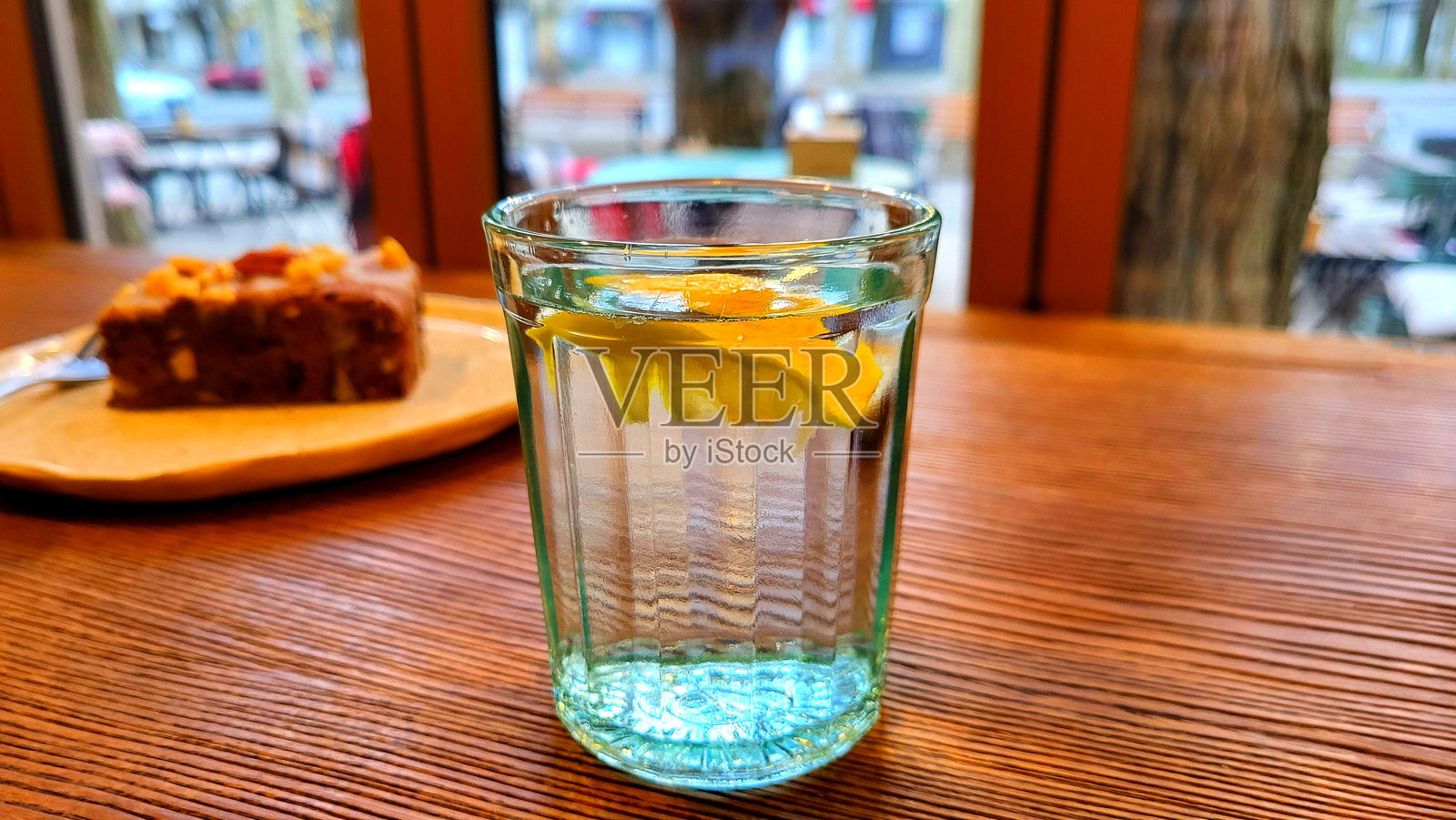 一杯水上面放着一片柠檬，静静地放在木桌上。照片摄影图片