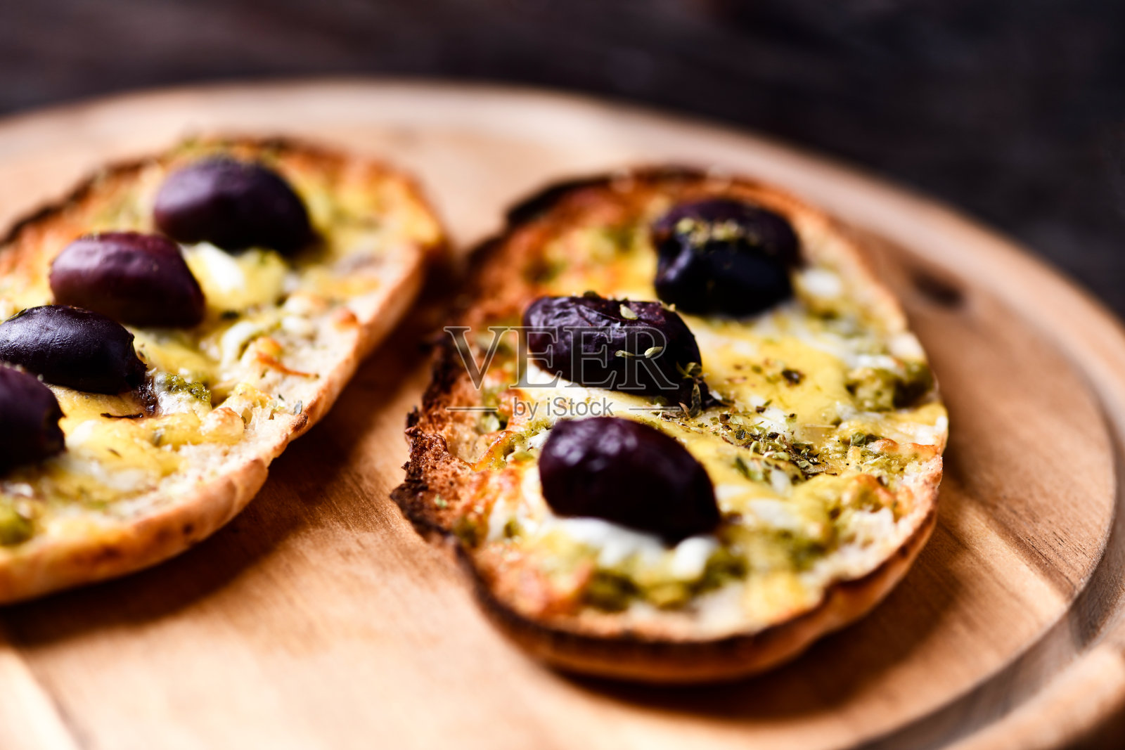 意式烤面包配马苏里拉和切达奶酪、橄榄香蒜酱和卡拉马塔橄榄，背景为木质纹理。柔焦特写。照片摄影图片