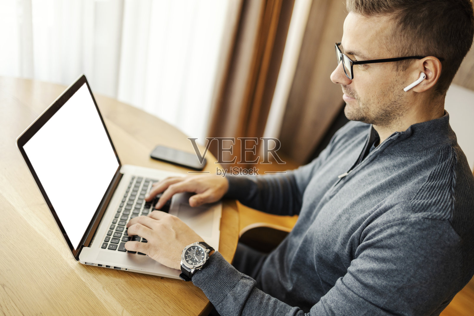 侧面视角的专注男子在家中使用笔记本电脑键盘打字。照片摄影图片