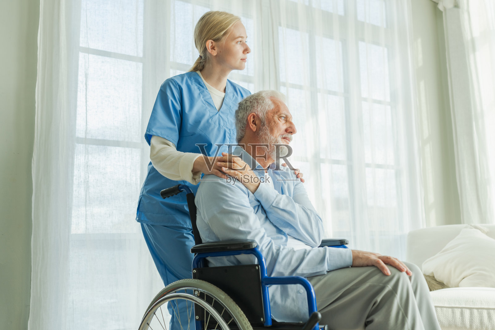 帮助支持退休医疗保健。护士在照顾坐在轮椅上的老人。病人与护理院的女性医疗护理人员，护士在照顾坐在椅子上的瘫痪男性，为残疾人士提供服务。照片摄影图片