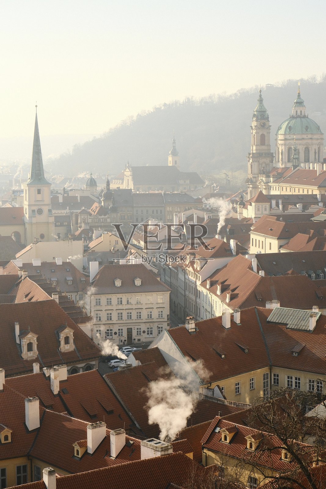 卢布尔雅那历史悠久的屋顶在晨雾中，烟囱冒出的烟雾升入空中照片摄影图片