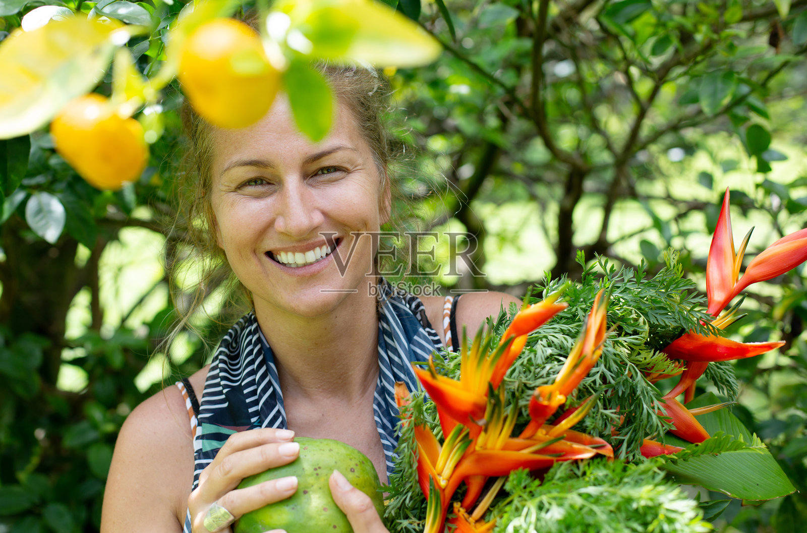 Cheerful and healthy living Middle-aged Woman in Hawaiian Nature Smiling and Holding Tropical Flowers and fruits照片摄影图片