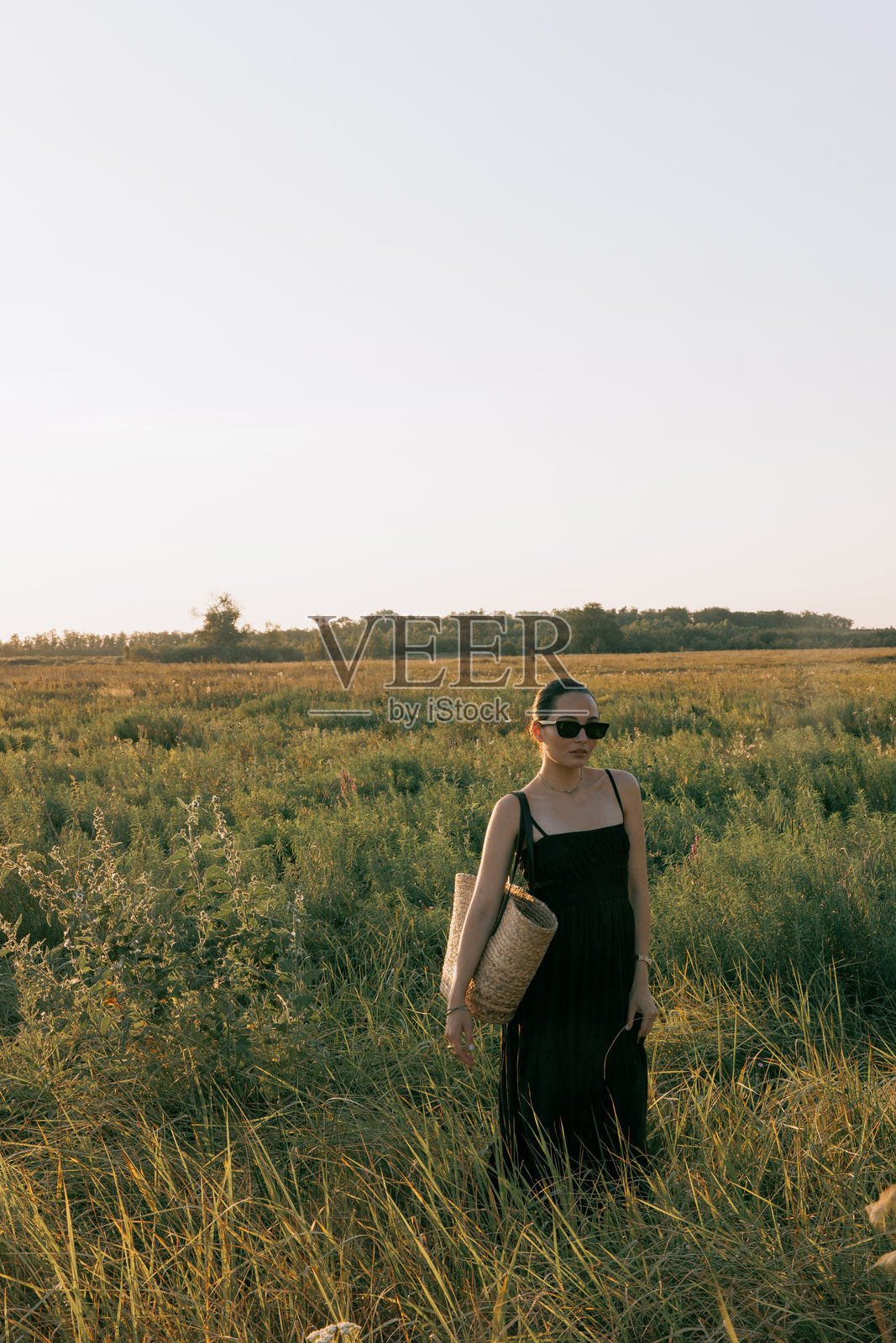 年轻女性在日落时分穿过草地上的草药。照片摄影图片