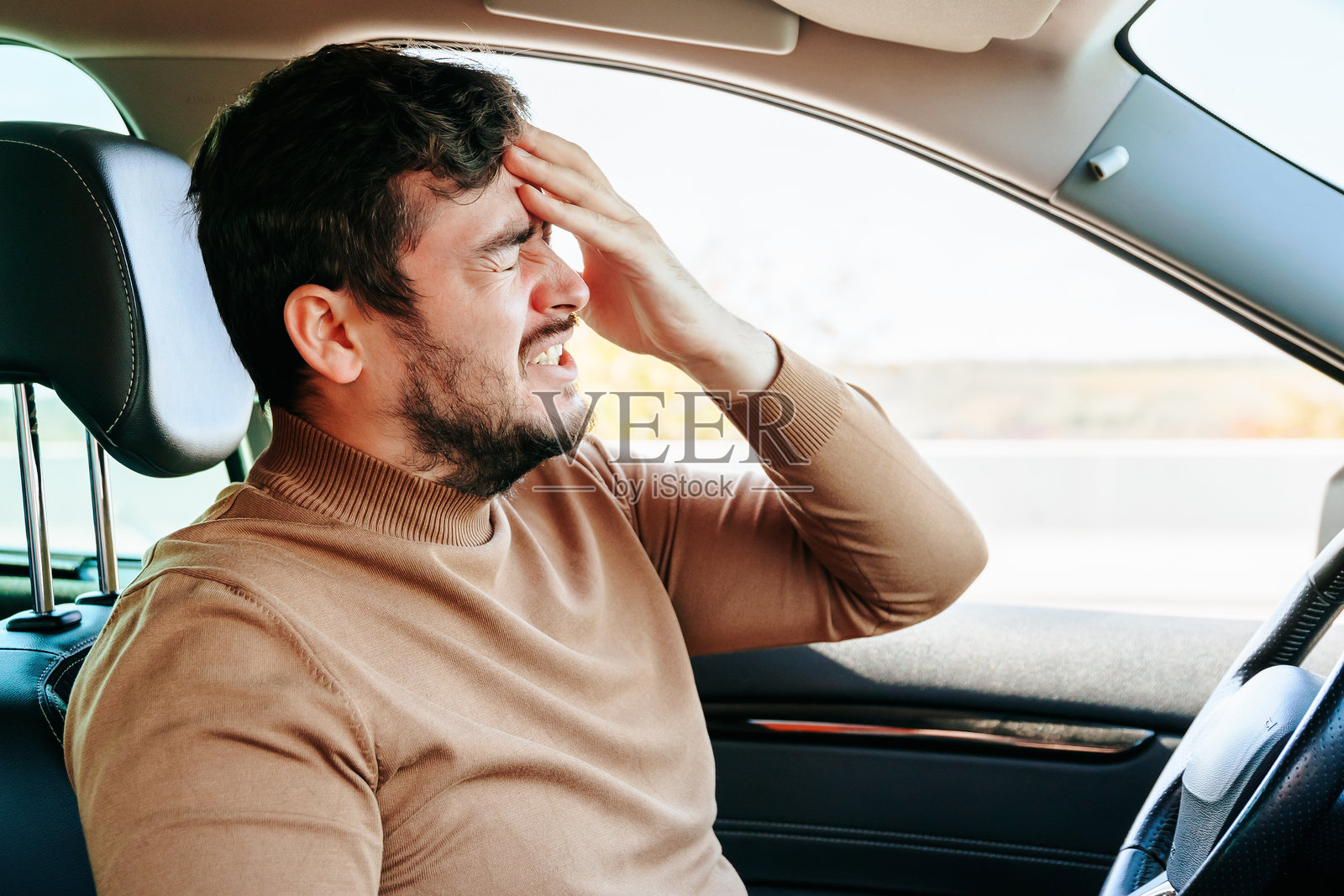 剧烈的头痛迫使男司机在路上停下，扭曲着他的脸。照片摄影图片