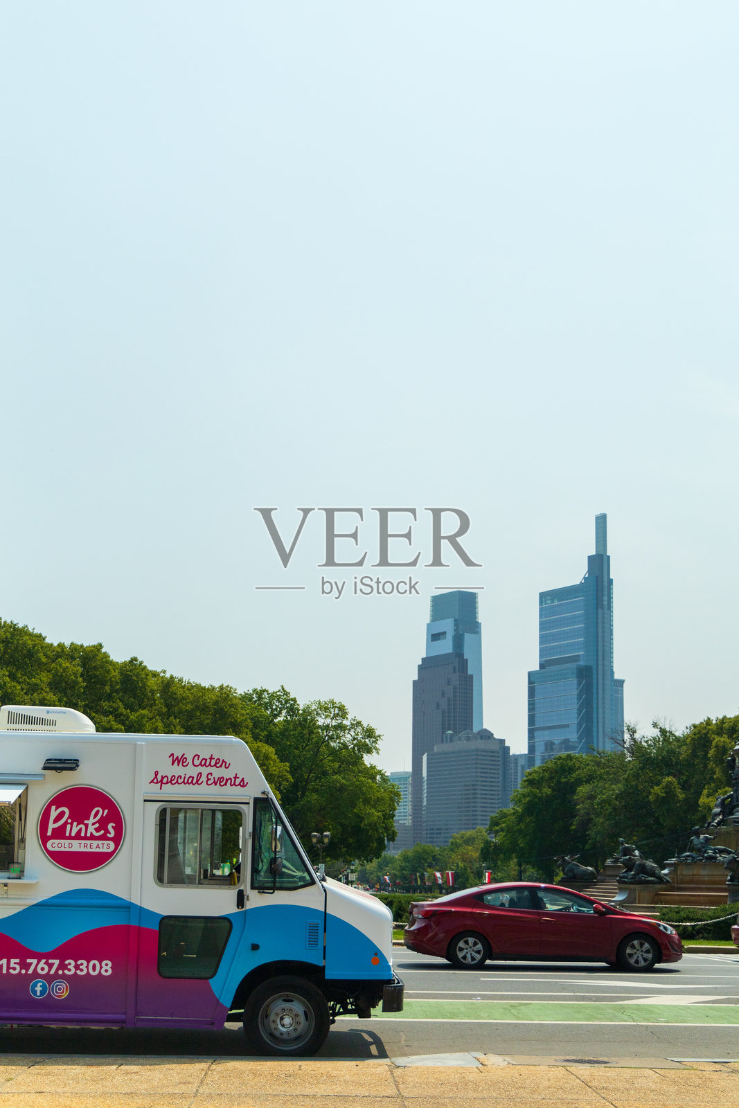 一辆粉色的餐车停在城市前面的一条路边。照片摄影图片