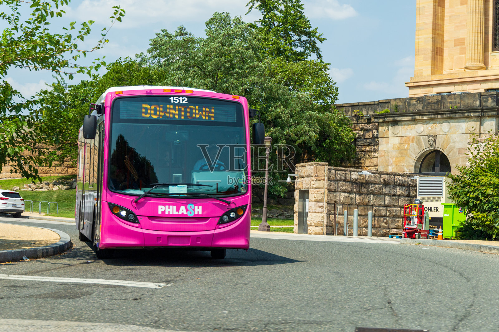 一辆前面标有15号的粉色PHLASH公交车正在街上行驶。照片摄影图片