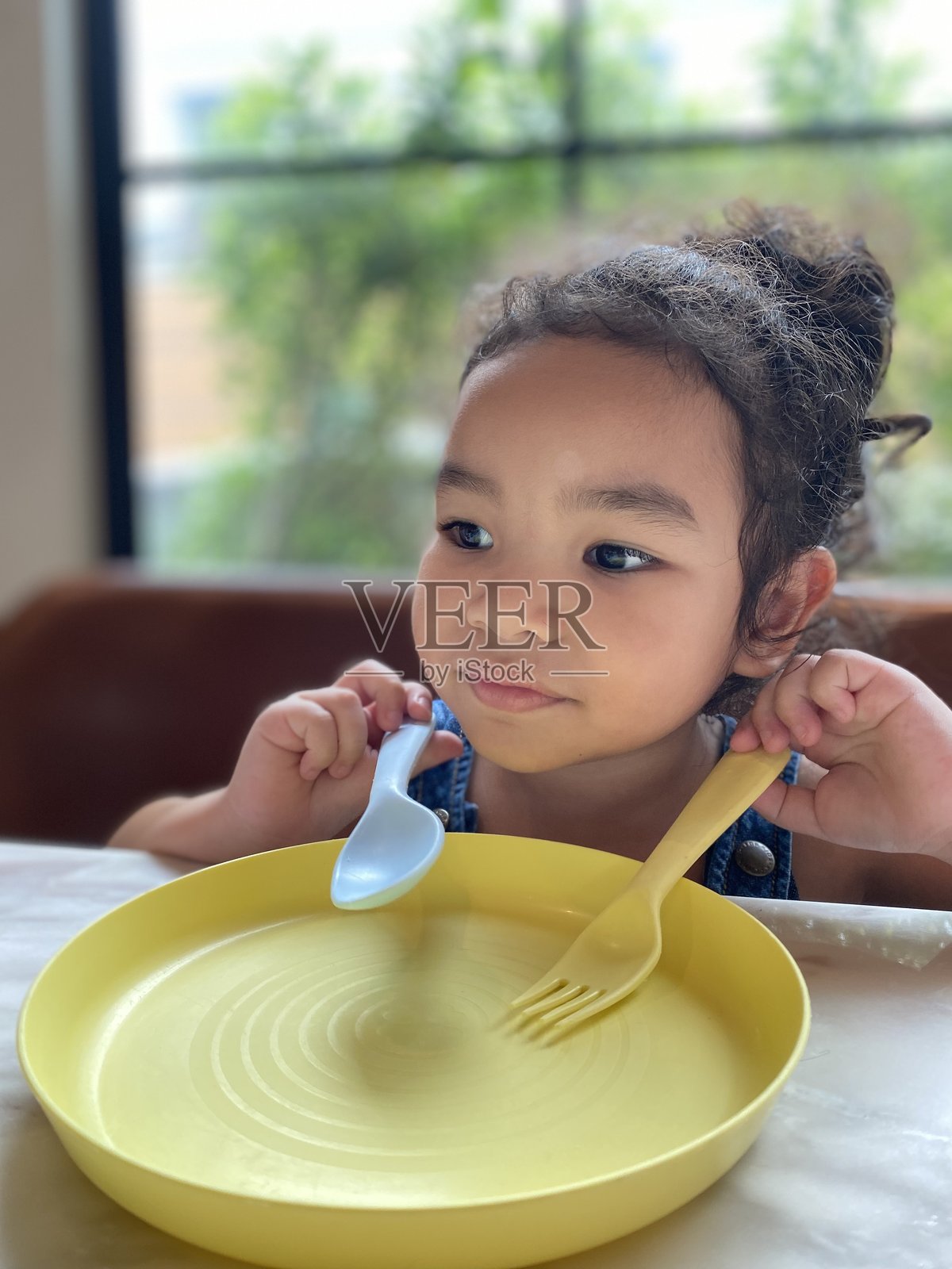 可爱的小女孩在家里用勺子和叉子吃东西的肖像照片摄影图片