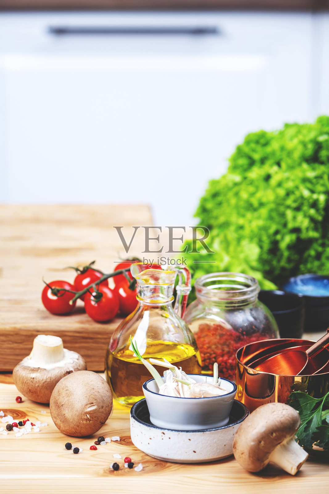 健康饮食、烹饪、食品博客背景。空的橡木砧板上放着西红柿、生菜、蔬菜和橄榄油，温馨的厨房里有木桌、厨房用具和食材。照片摄影图片