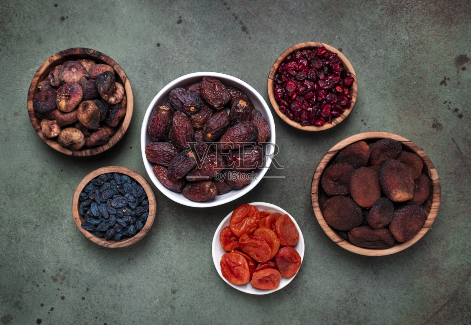 绿色背景上的有机日晒水果盛在碗中。健康的零食替代糖果和糖。俯视图照片摄影图片